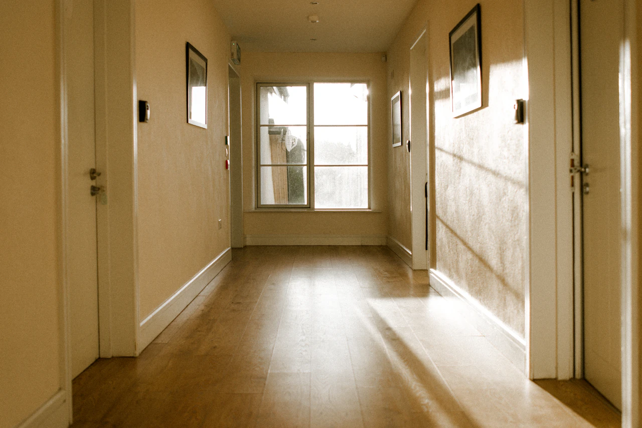 Warm sunlight crossing the floor of a quiet residential hallway.